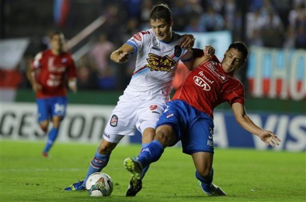 Julio Furch del Arsenal de Argentina (izquierda) disputa un balón con José Cáceres de Nacional de Paraguay en el partido por los cuartos de final de la Copa Libertadores en Buenos Aires, el miércoles 14 de mayo de 2014. (AP Foto/Natacha Pisarenko)