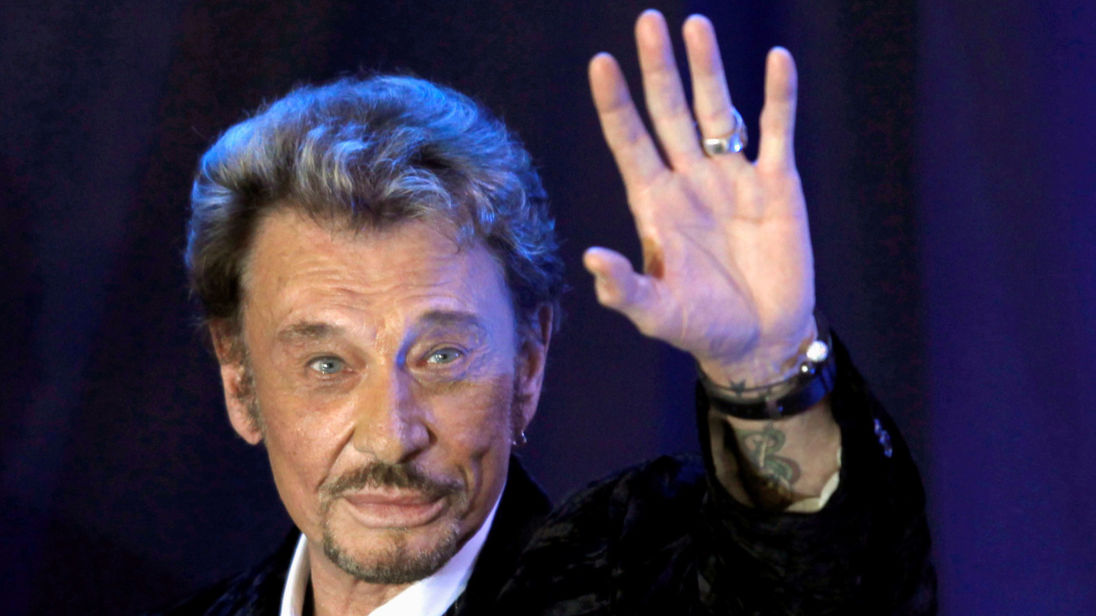 FILE PHOTO: French singer Johnny Hallyday waves to fans attending a ceremony to promote his new album «Jamais seul» (Never alone) at the Virgin Megastore in Paris