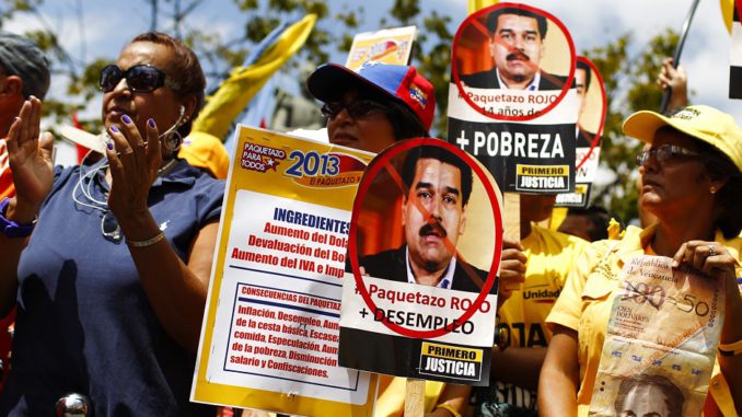Opposition supporters hold posters of Venezuela's VP Maduro during a rally to protest against economic measures, in Caracas