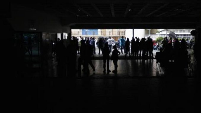 People stand outside a shopping mall during a massive blackout in Caracas