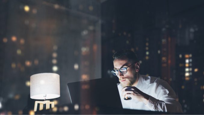Bearded young businessman working on modern loft office at night