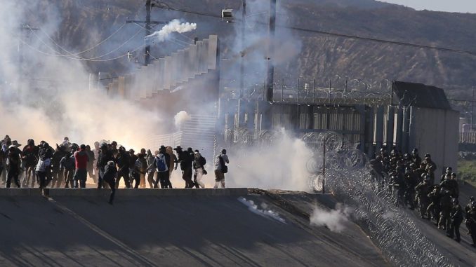 Migrantes intentan cruzar muro con EE.UU. y reciben gas lacrimógeno