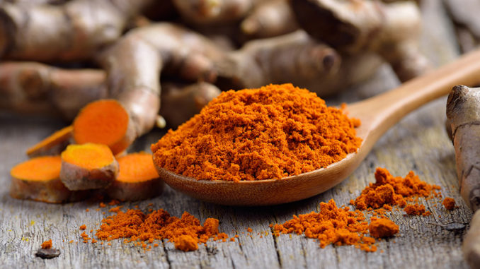 pile of fresh turmeric roots on wooden table