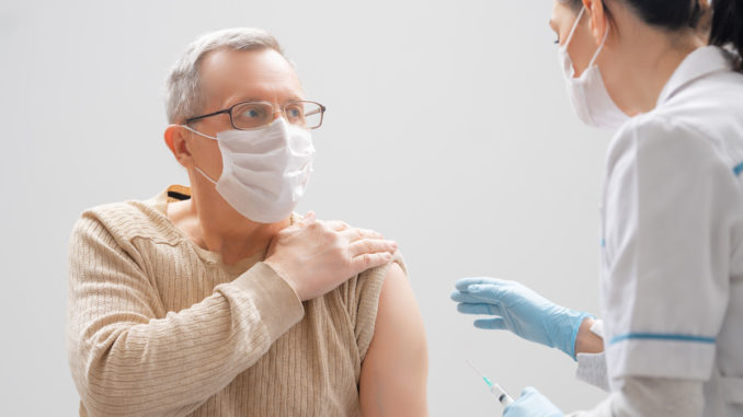Doctor giving a senior man a vaccination