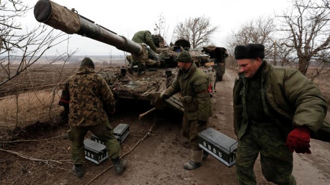 Pro-Russian separatists walk near a tank in Donetsk region