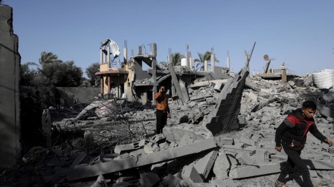 Palestinians walk among rubble of buildings in Al-Nuseirat refugee camp