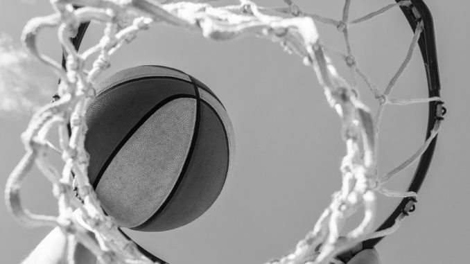 ball goes through basket. man throw the ball in hoop. hands and basketball.